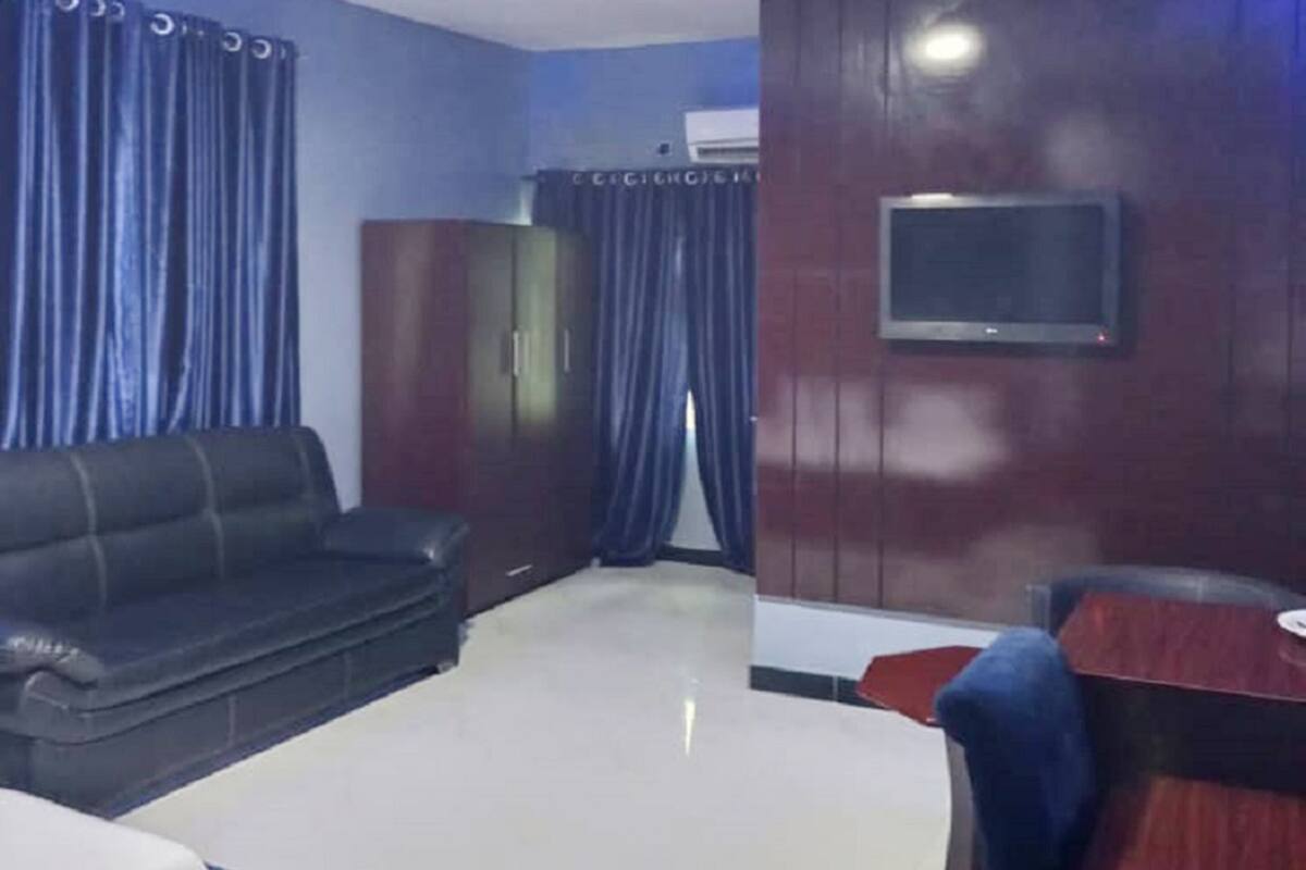 A modern living room with a sofa, a coffee table, a TV mounted on a wooden wall, and a desk with a chair.