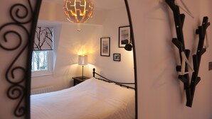 A bedroom with a bed, a lamp, a globe light, and a window. - Kings Cross Apartments (London)