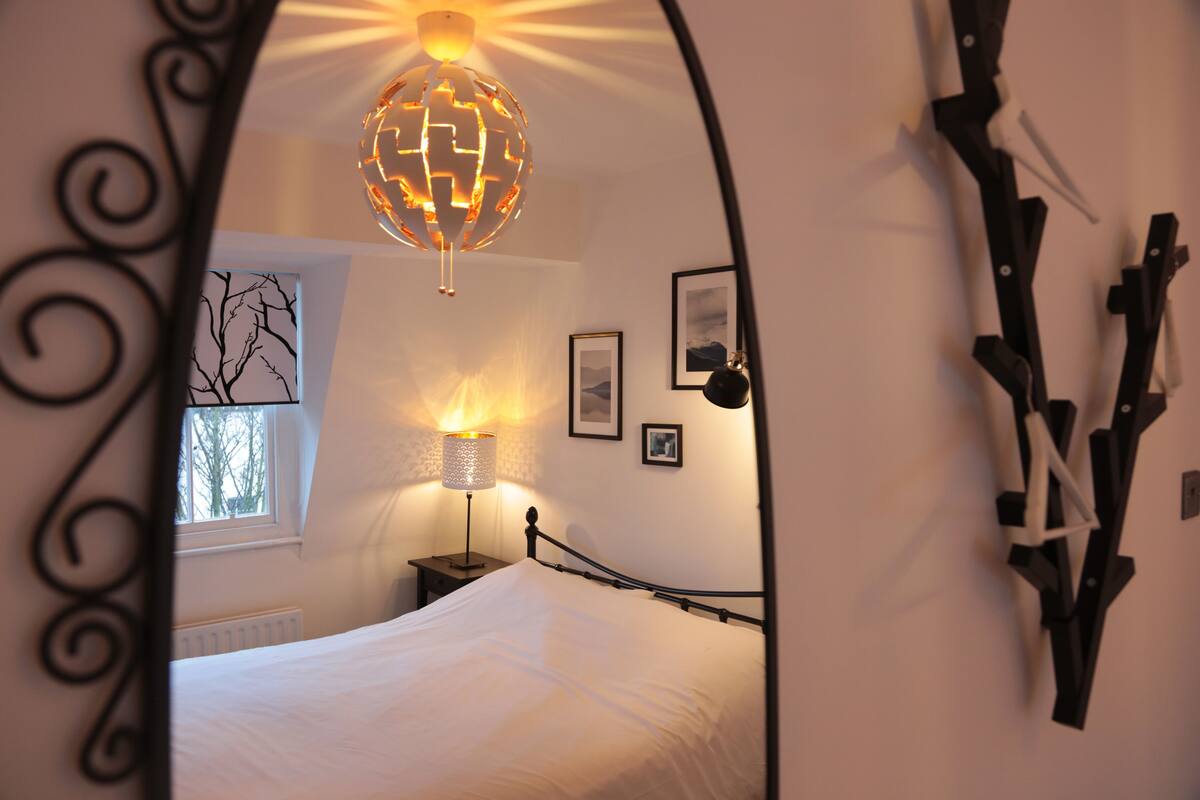 A bedroom with a bed, a lamp, a globe light, and a window.