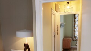 A hallway with wooden flooring, a lamp, a radiator, and a door leading to another room. - Kings Cross Apartments (London)