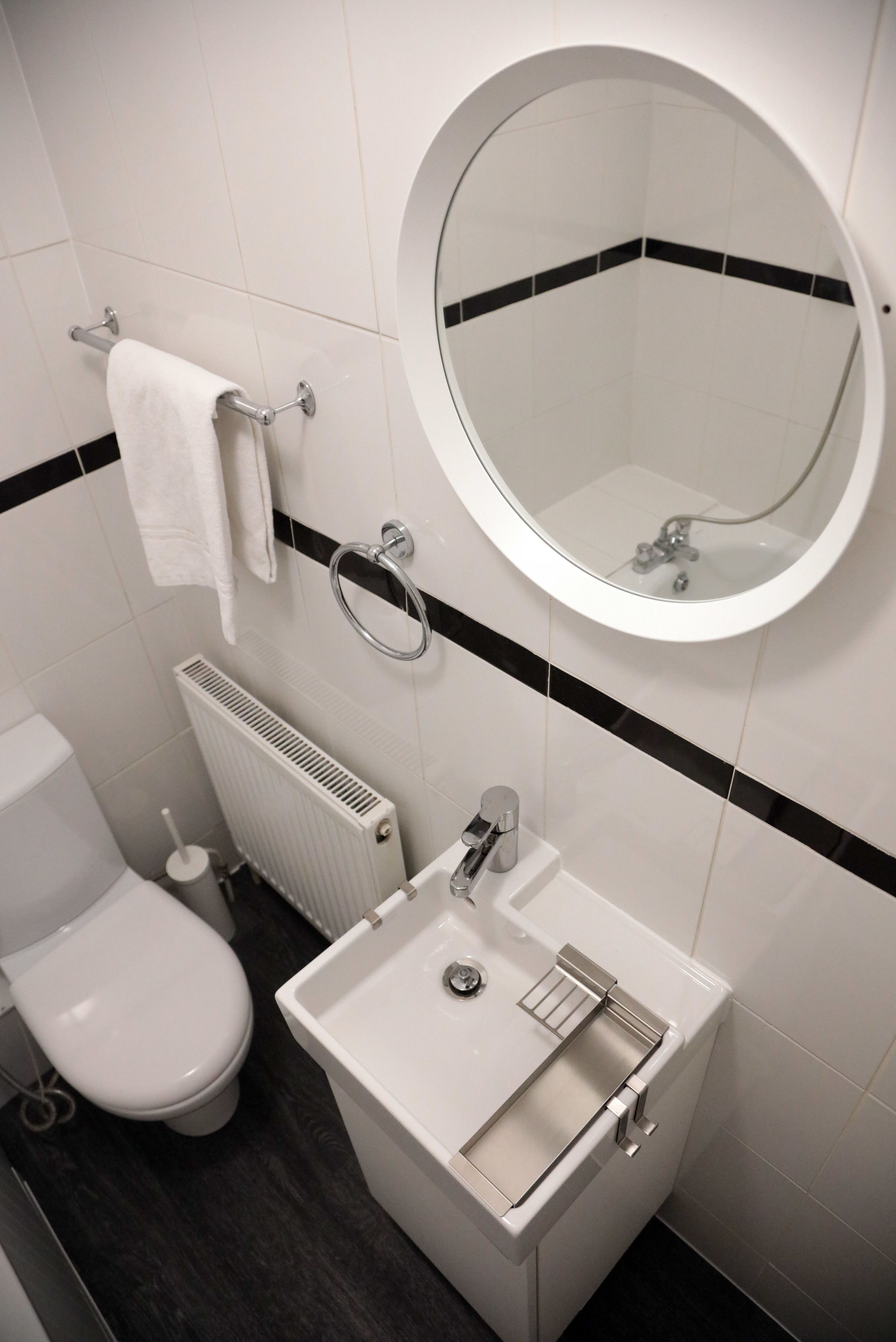 Une salle de bain équipée de toilettes, d’un lavabo, d’un miroir et d’un porte-serviettes.