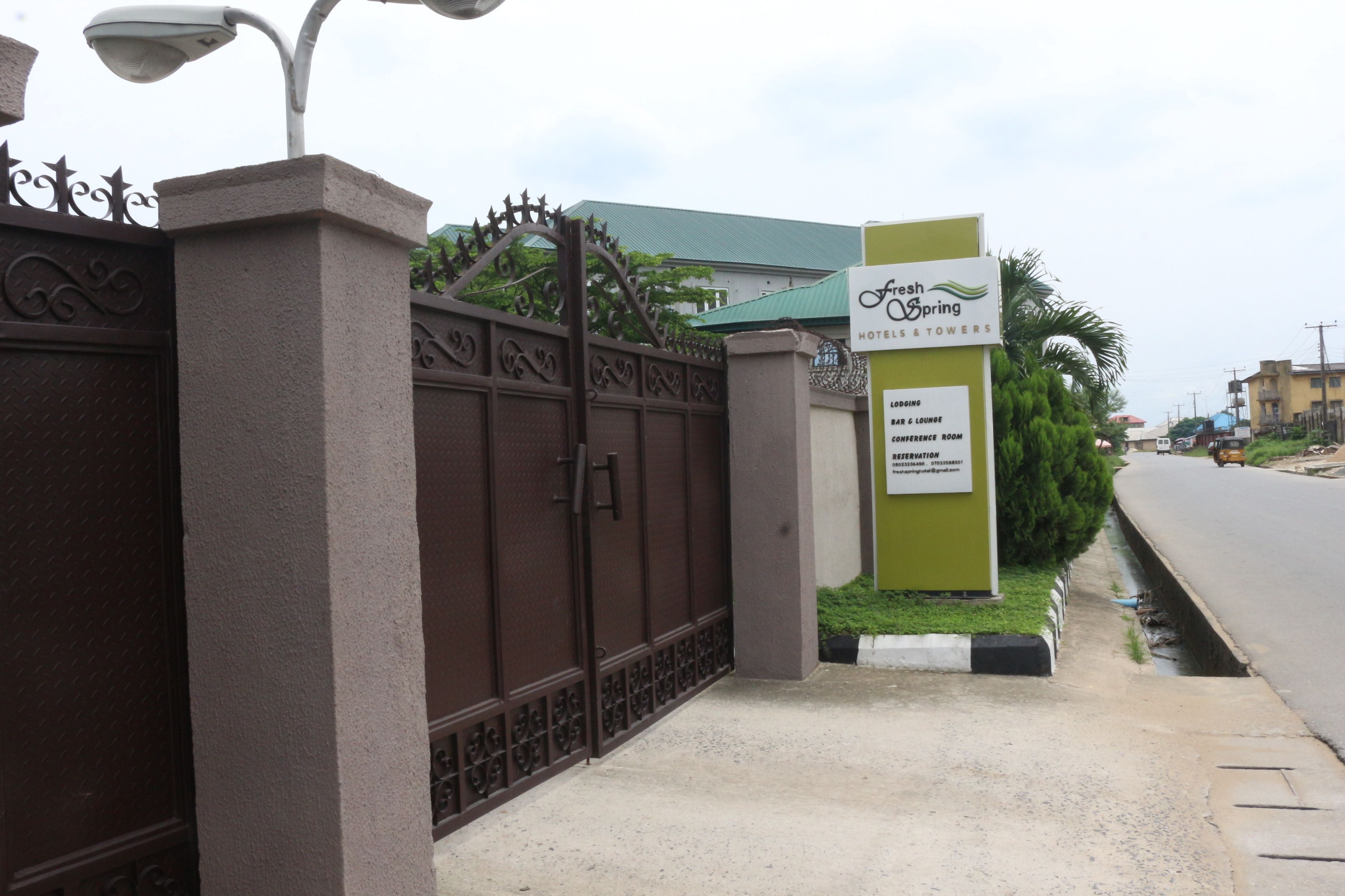 A gated entrance to a hotel with a sign listing amenities such as a bar, conference room, and lounge.