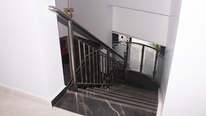 A modern staircase with metal railings and a handrail, leading to a room with a door labeled "LOX". - Fresh Spring Hotels & Towers (Uyo)