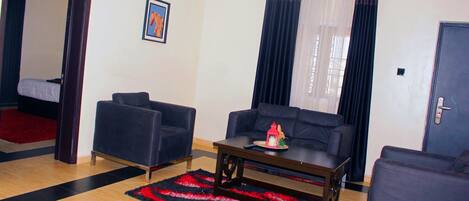 A living room with a sofa, armchairs, a coffee table, and a red and black rug.