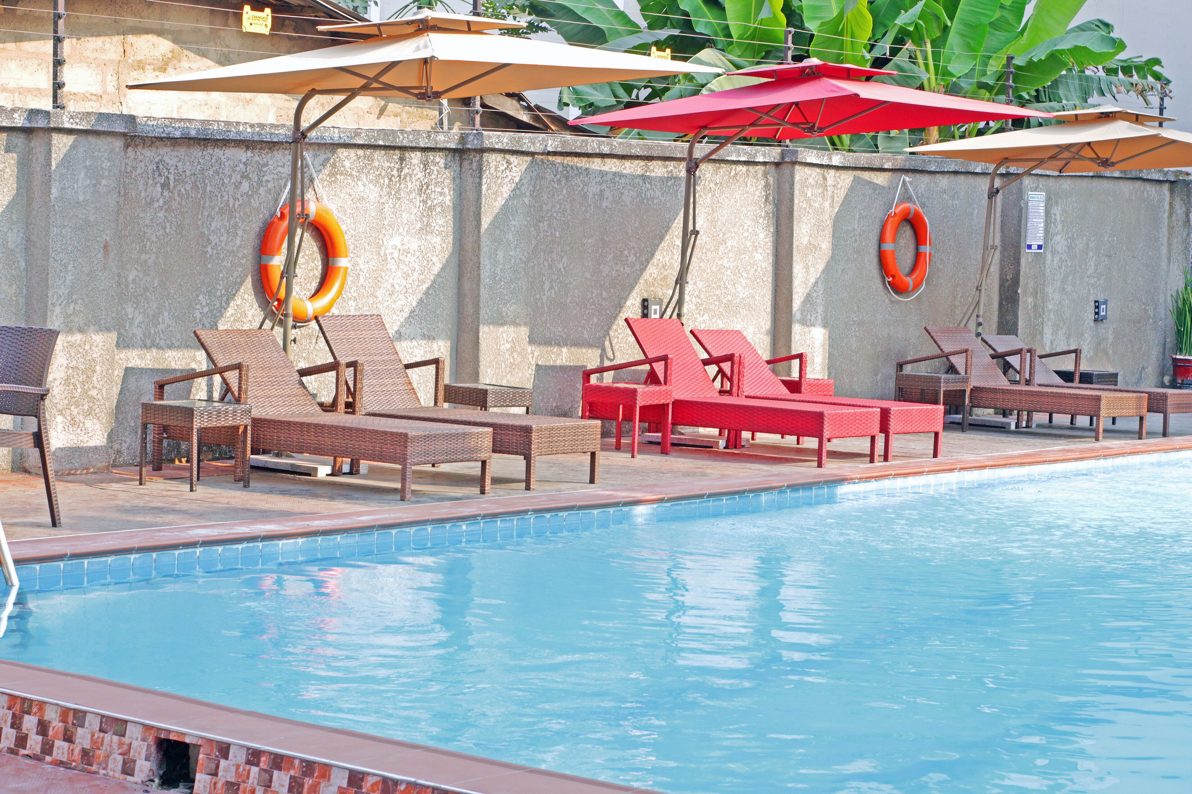 Un área de piscina con sillones de descanso y sombrillas.