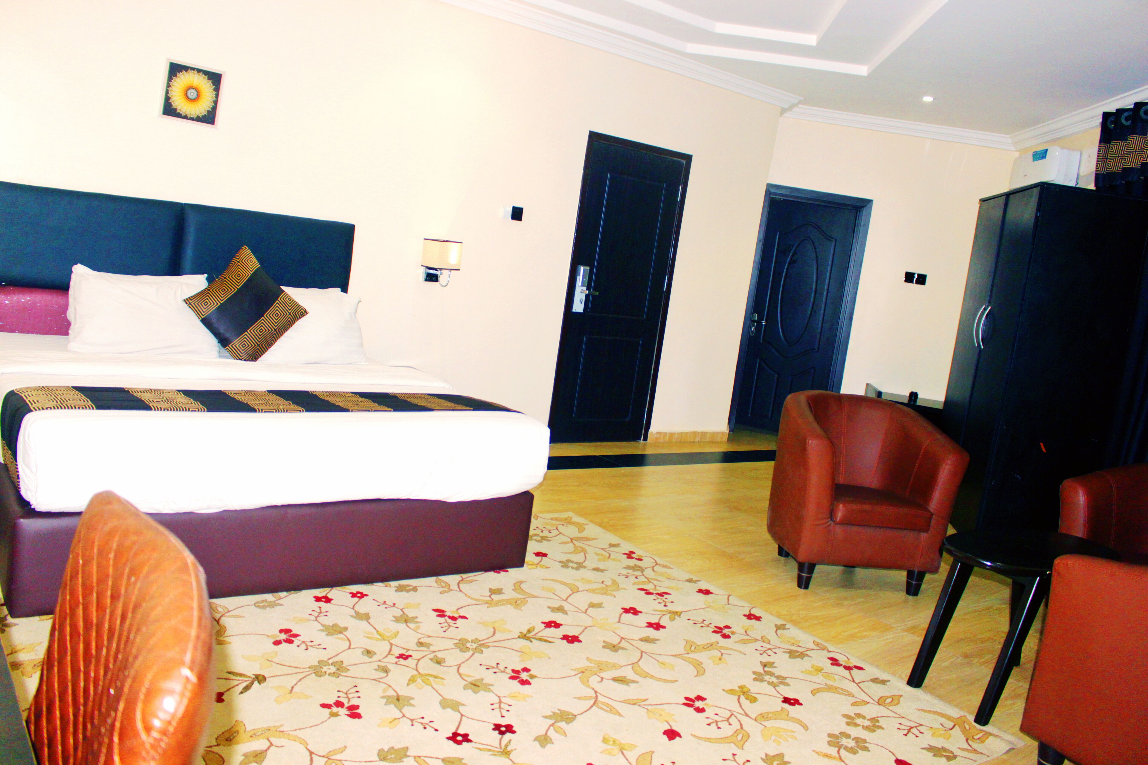 Ein Hotelzimmer mit Bett, Sessel, Schreibtisch und Kleiderschrank.