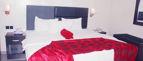 A hotel room with a large bed, a nightstand, a lamp, and a wall-mounted phone.