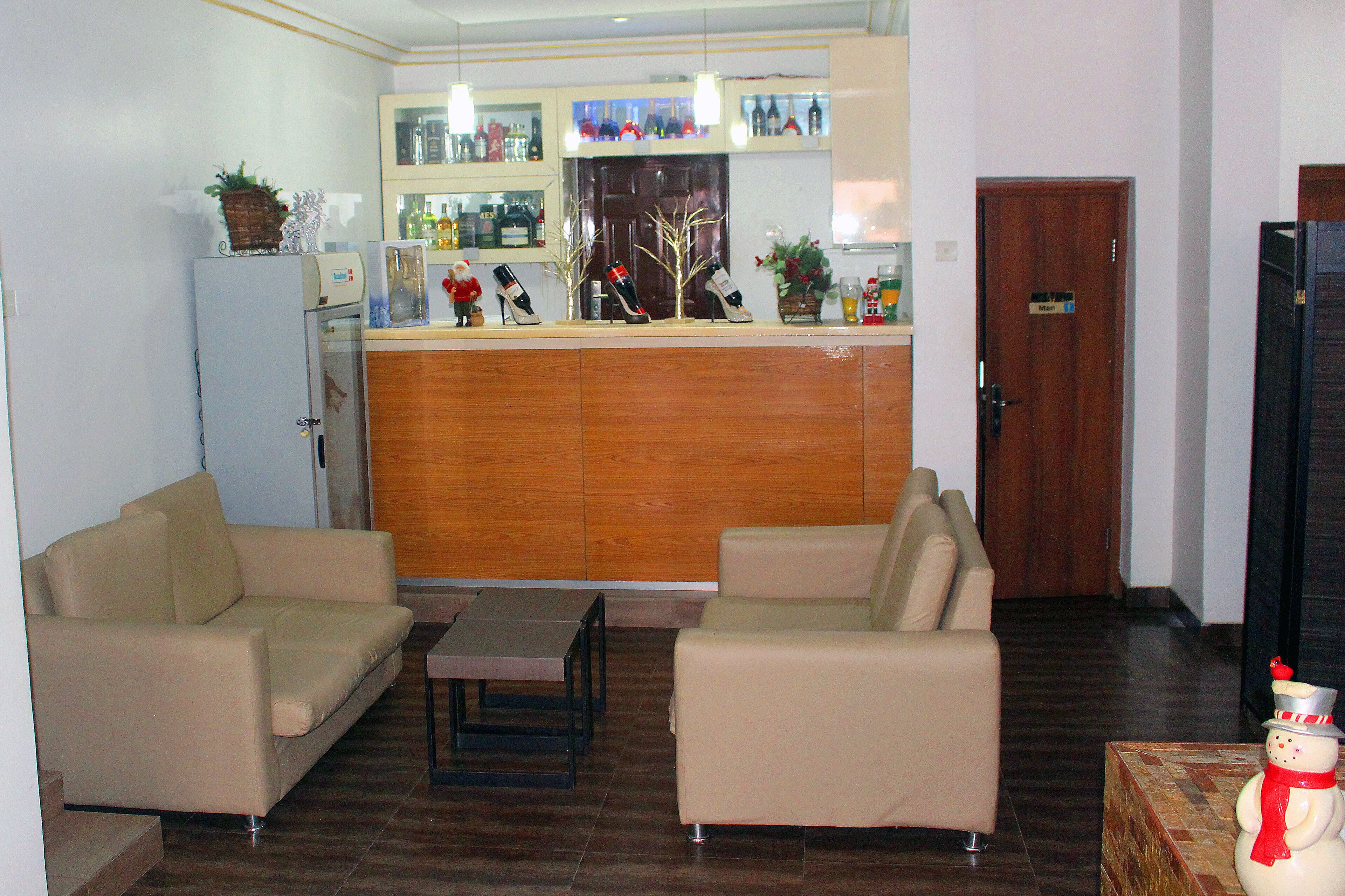 Un salon avec deux canapés beige, une table basse et un meuble en bois contenant des bouteilles et des objets de décoration.