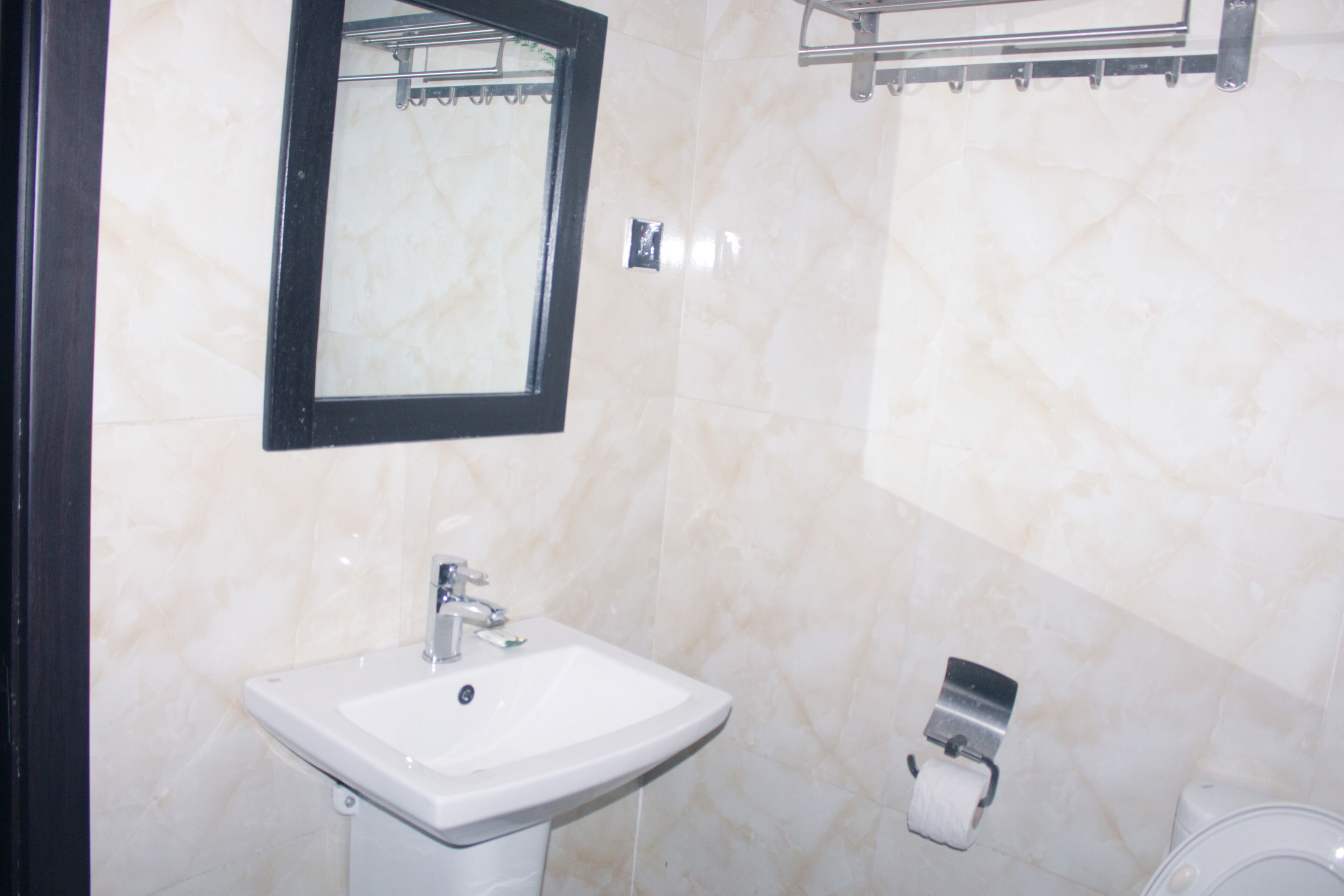 Une salle de bain avec un lavabo blanc, un miroir et des toilettes.