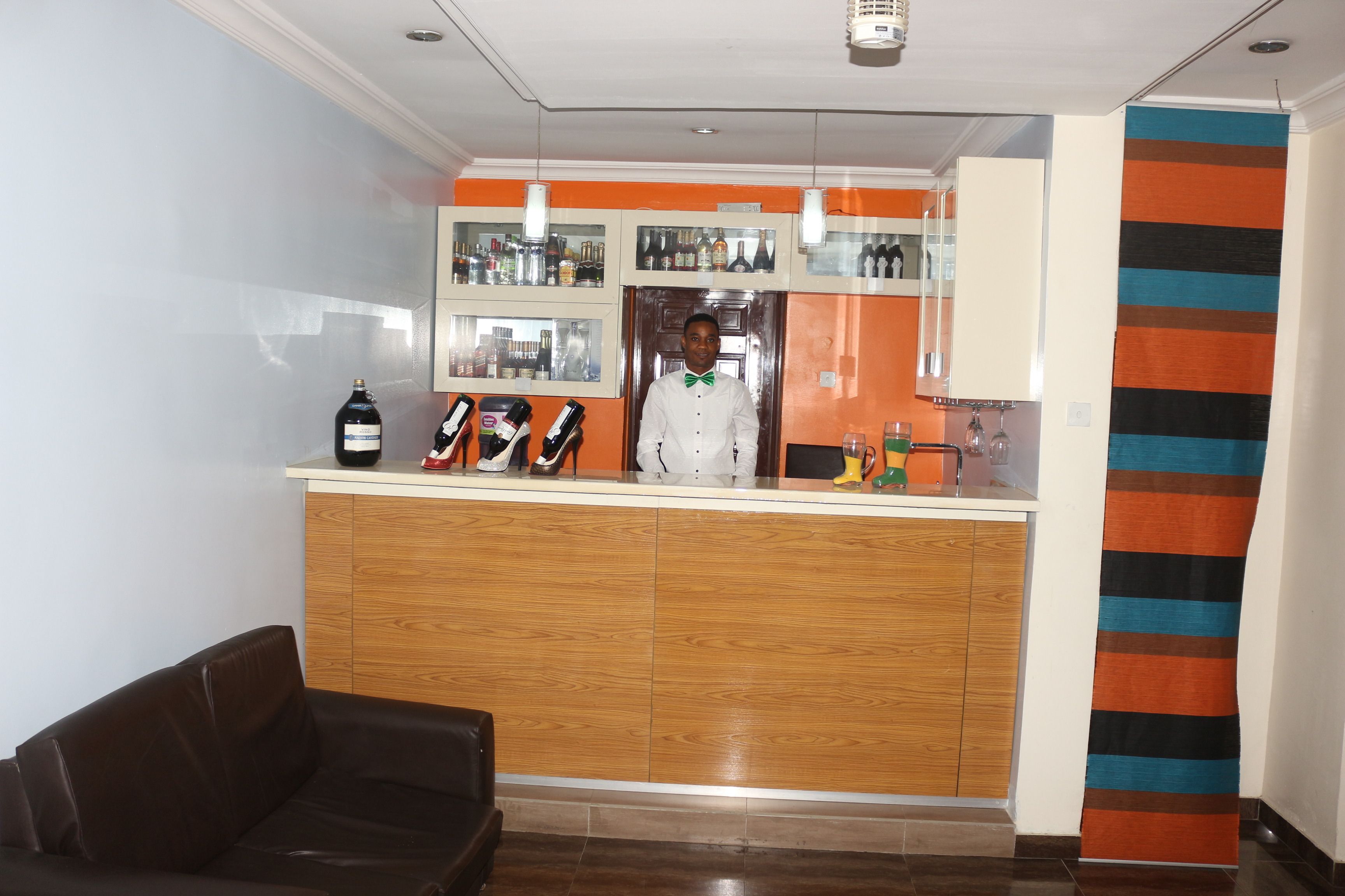 A reception area with a wooden counter, a black leather couch, and a striped curtain.
