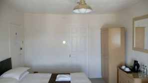 Ein Hotelzimmer mit Bett, Schrank, Spiegel und Nachttisch mit Lampe.