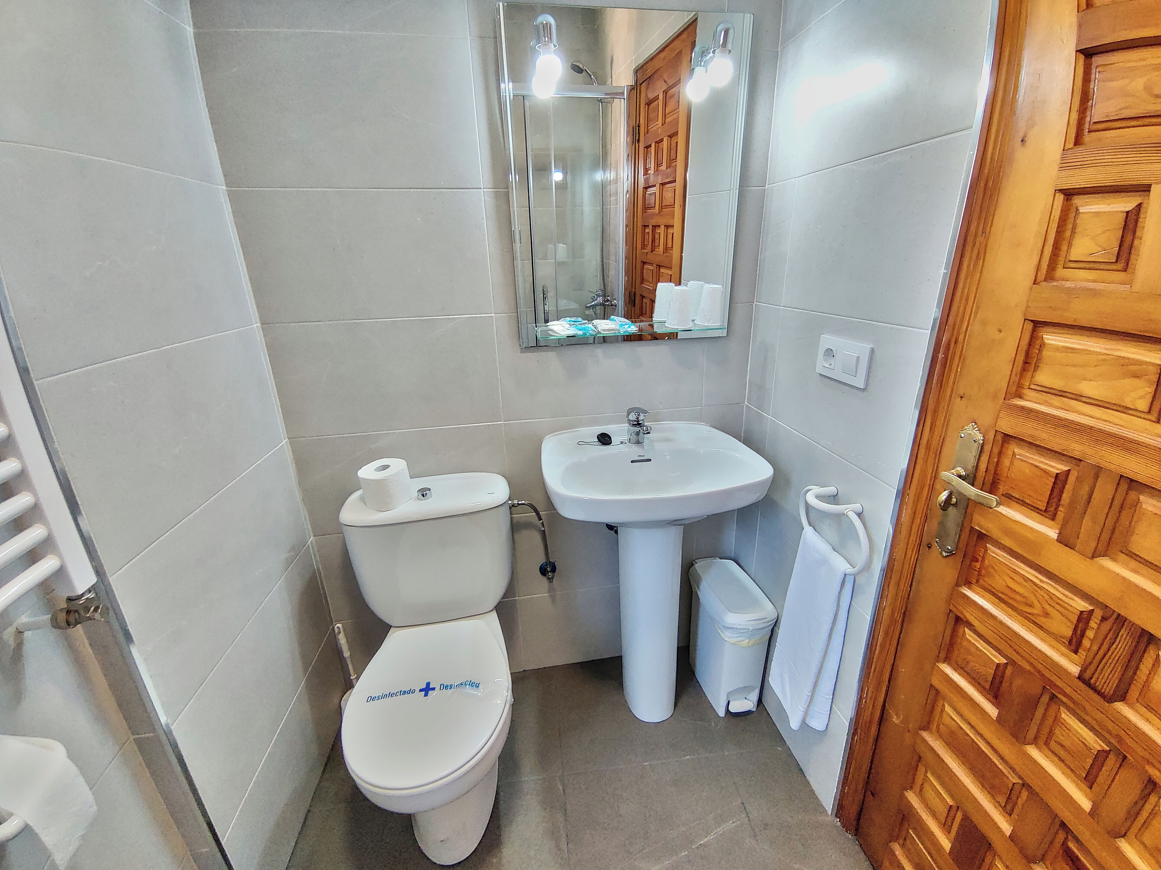 A small, clean bathroom with a toilet, sink, and mirror.