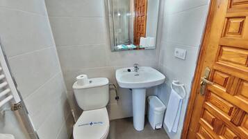 A small, clean bathroom with a toilet, sink, and mirror.