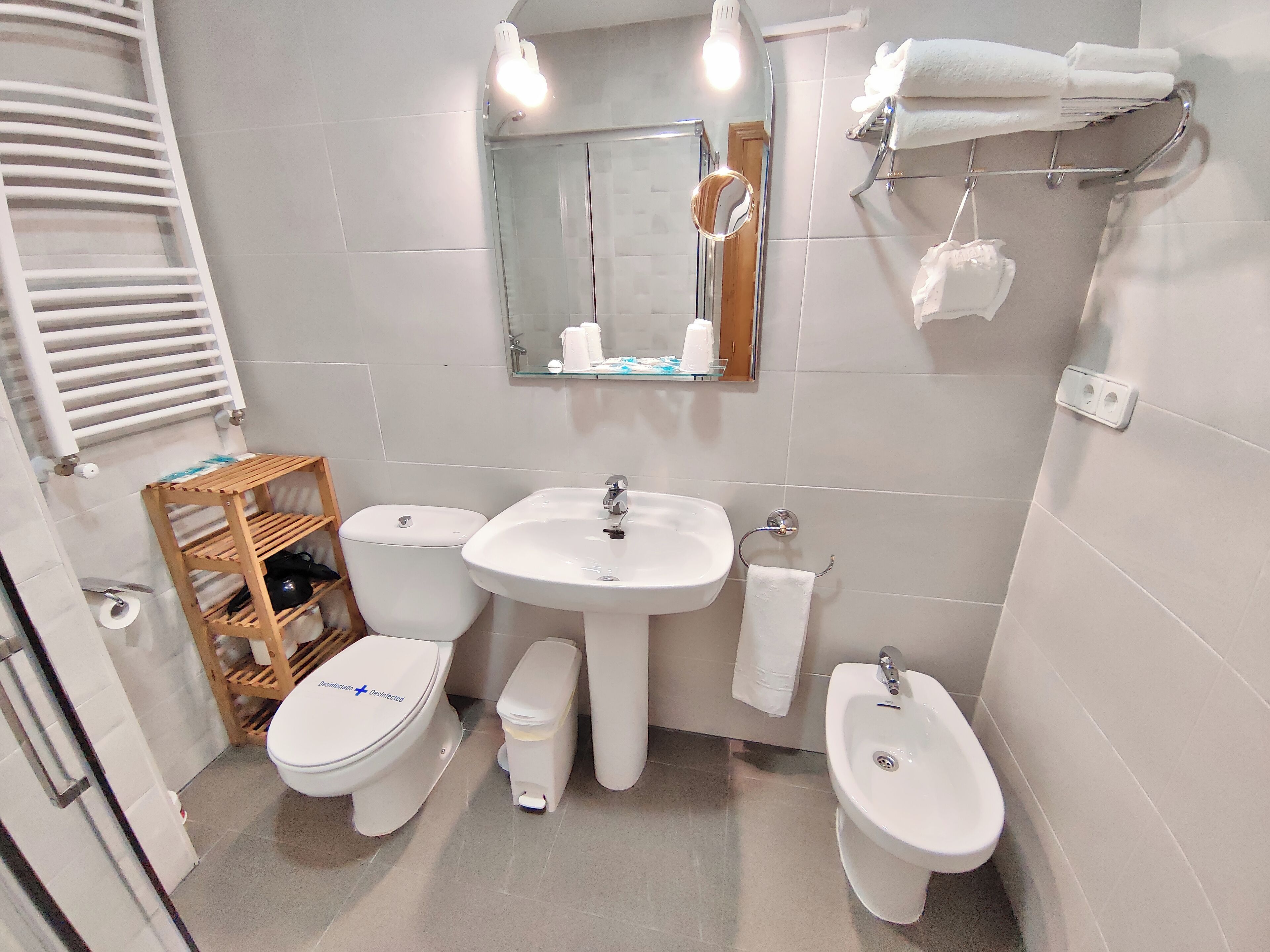 A modern bathroom with a toilet, bidet, sink, and towel rack.