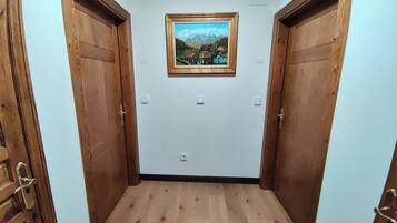 A narrow hallway with wooden doors on either side and a framed painting on the wall.