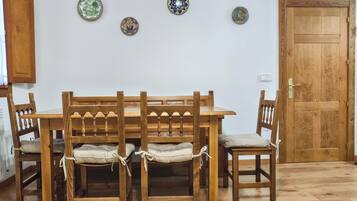 A wooden dining table with four chairs, a wooden door, and three decorative plates on the wall.