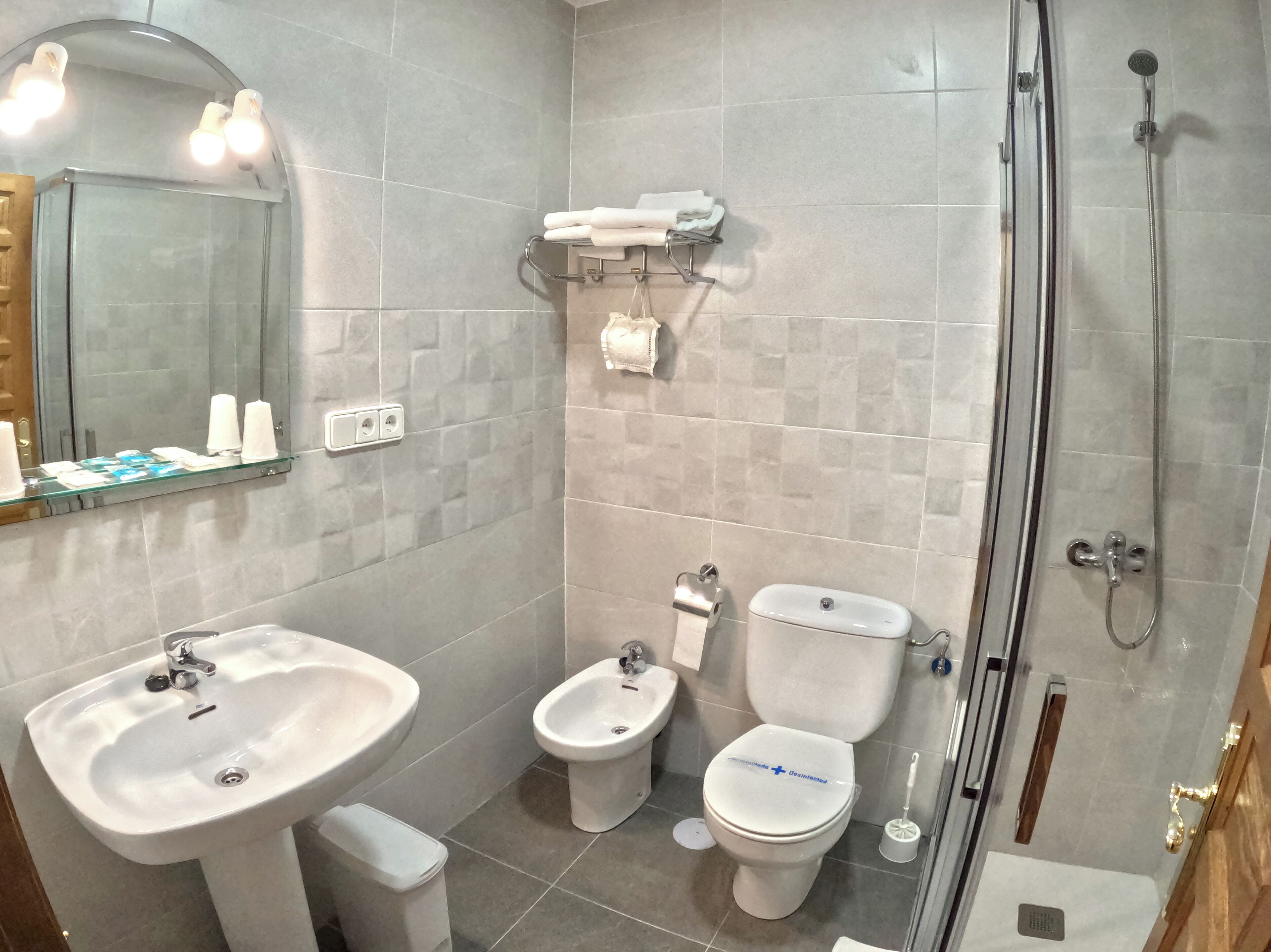 Un baño moderno con cabina de ducha de vidrio, lavamanos, un bidé y un inodoro.
