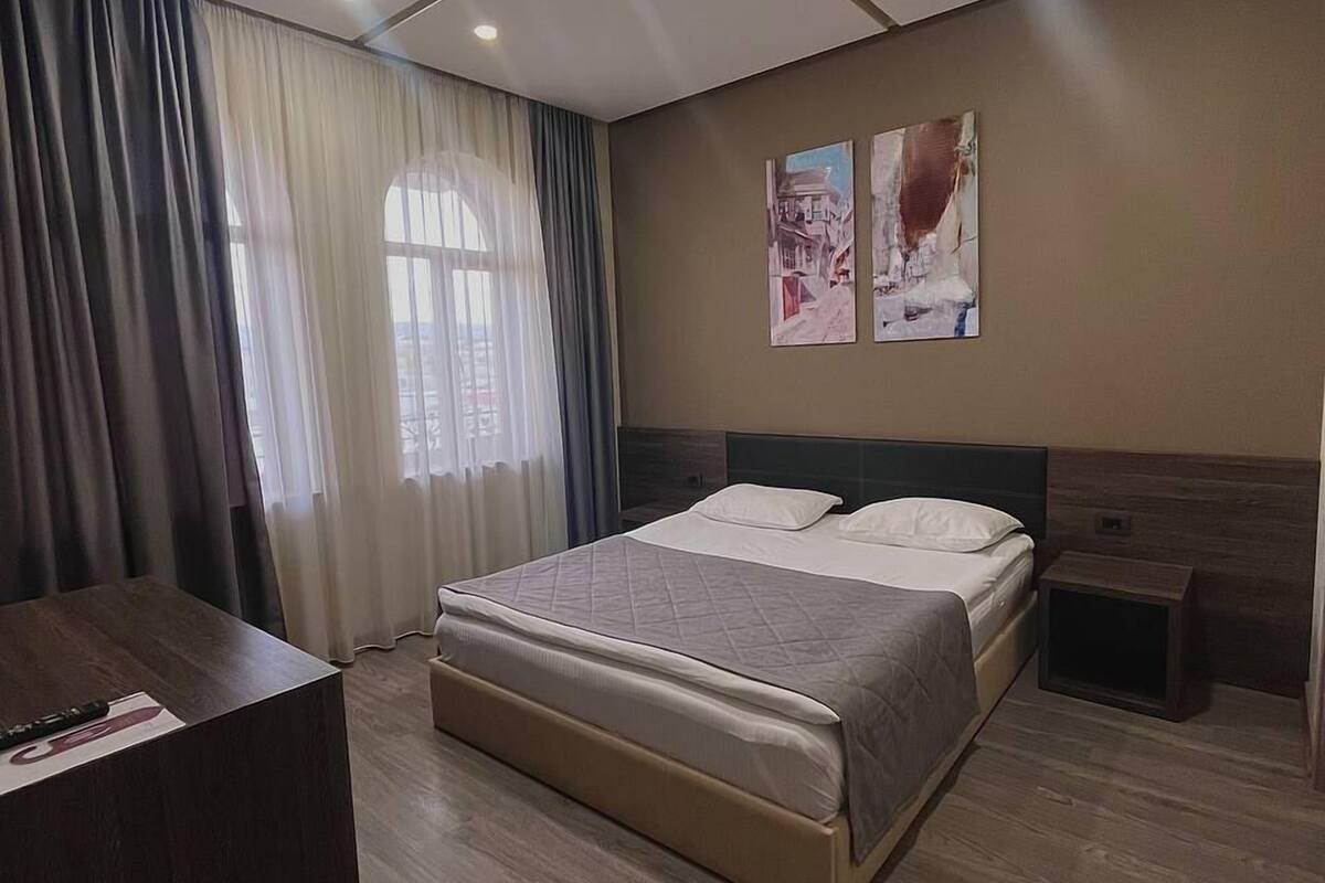 A modern bedroom with a large bed, a desk, and a nightstand.