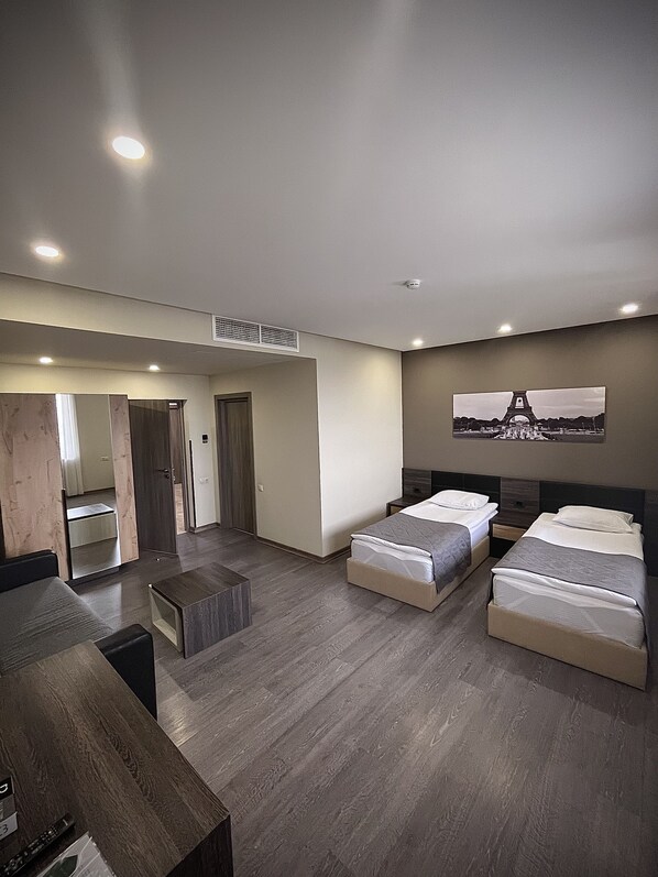 Una habitación de hotel moderna con dos camas, un escritorio, un espejo y una imagen de la Torre Eiffel en la pared.