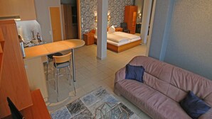 A compact living space with a kitchenette, a bed, a sofa, and a dining area. - Hotel Garni Haffmans (Grefrath)