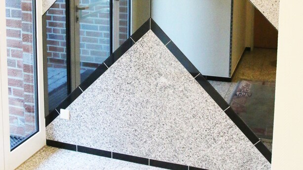 A modern interior with a geometric wall design, a brick wall, and a glass door. - Hotel Garni Haffmans (Grefrath)