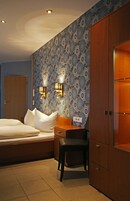 Una habitación de hotel con una cama, un escritorio, una silla y un armario.
