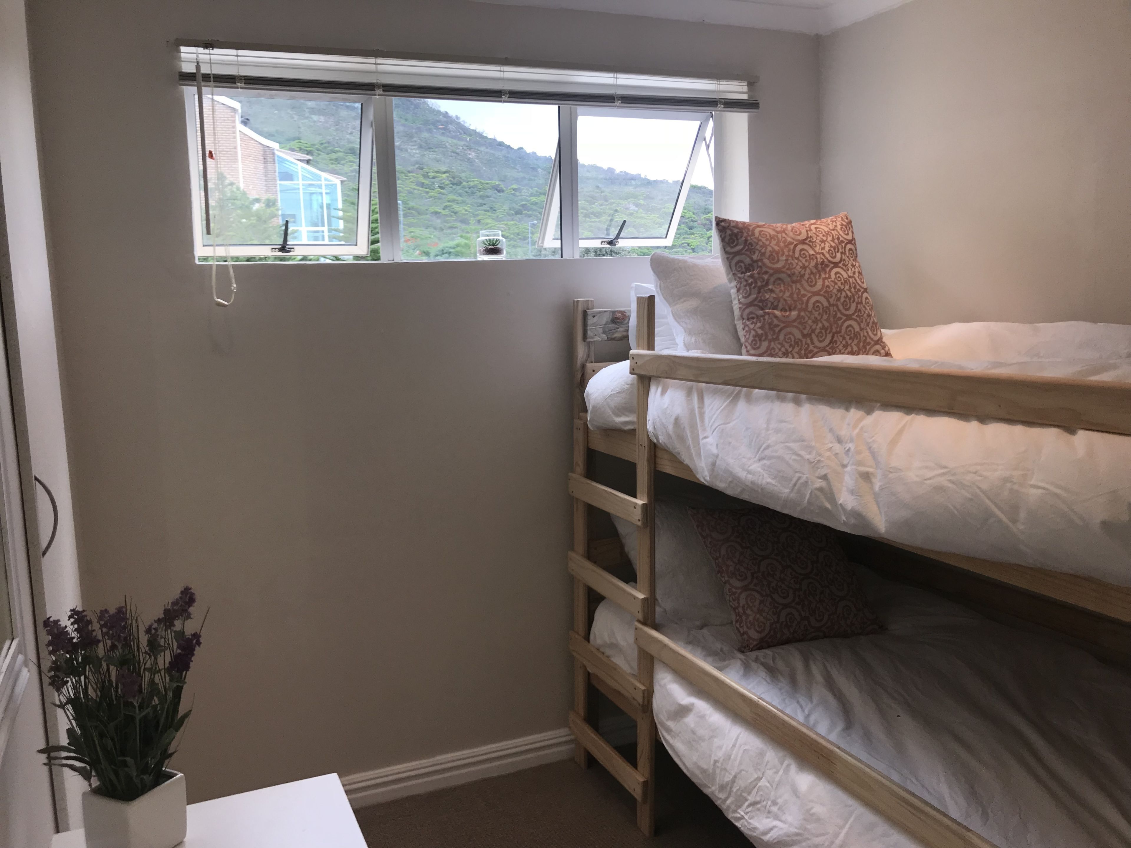 A bunk bed room with a window overlooking a mountain.