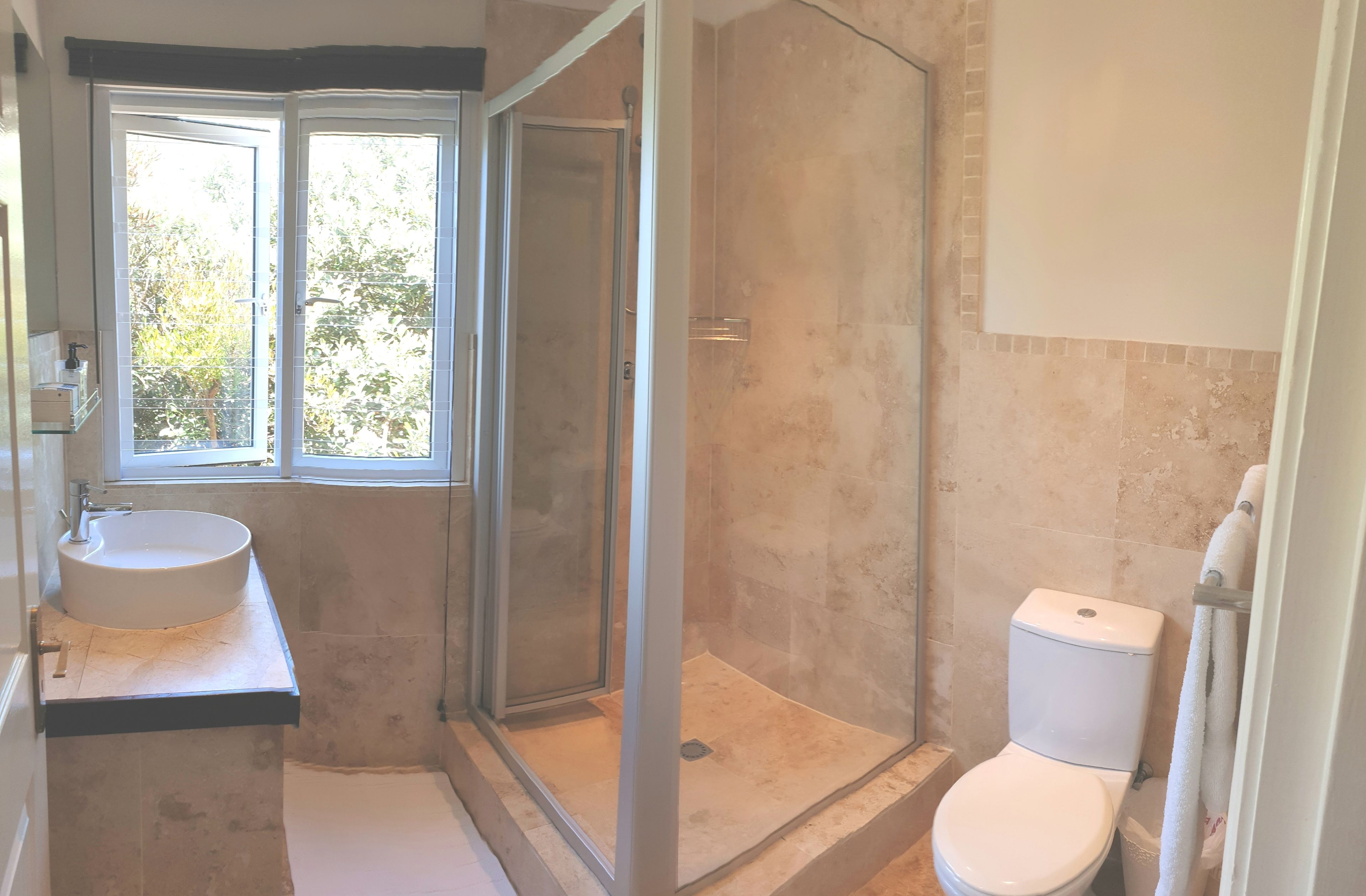 A bathroom with a glass-enclosed shower, a toilet, and a sink.