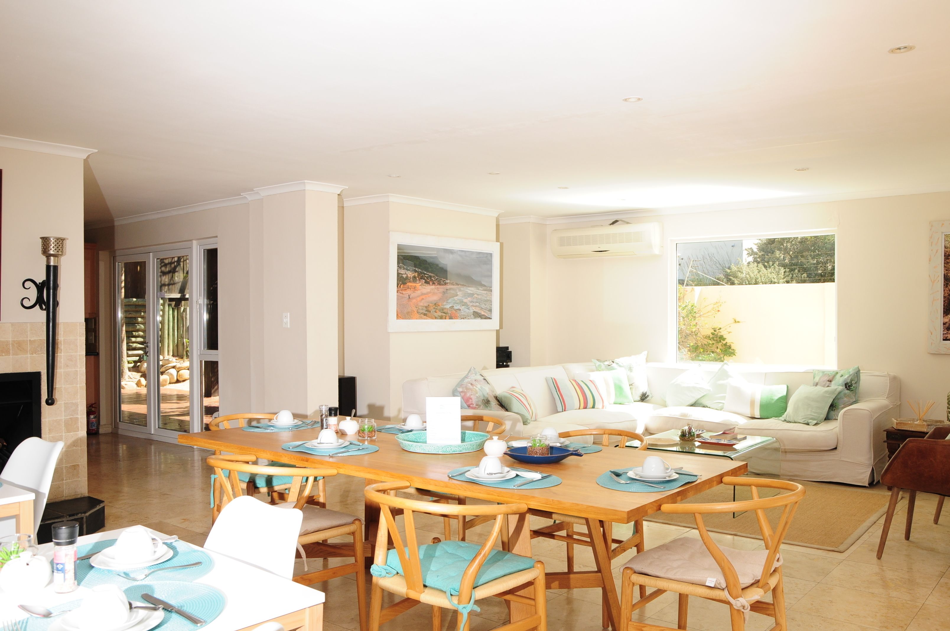 A spacious living area with a dining table set for four, a sofa, and a fireplace.