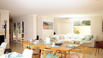 A spacious living area with a dining table set for four, a sofa, and a fireplace.