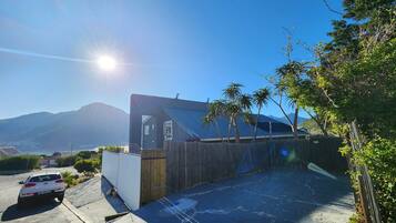 A modern building with a sloped roof, a parking area, and a view of mountains in the background.