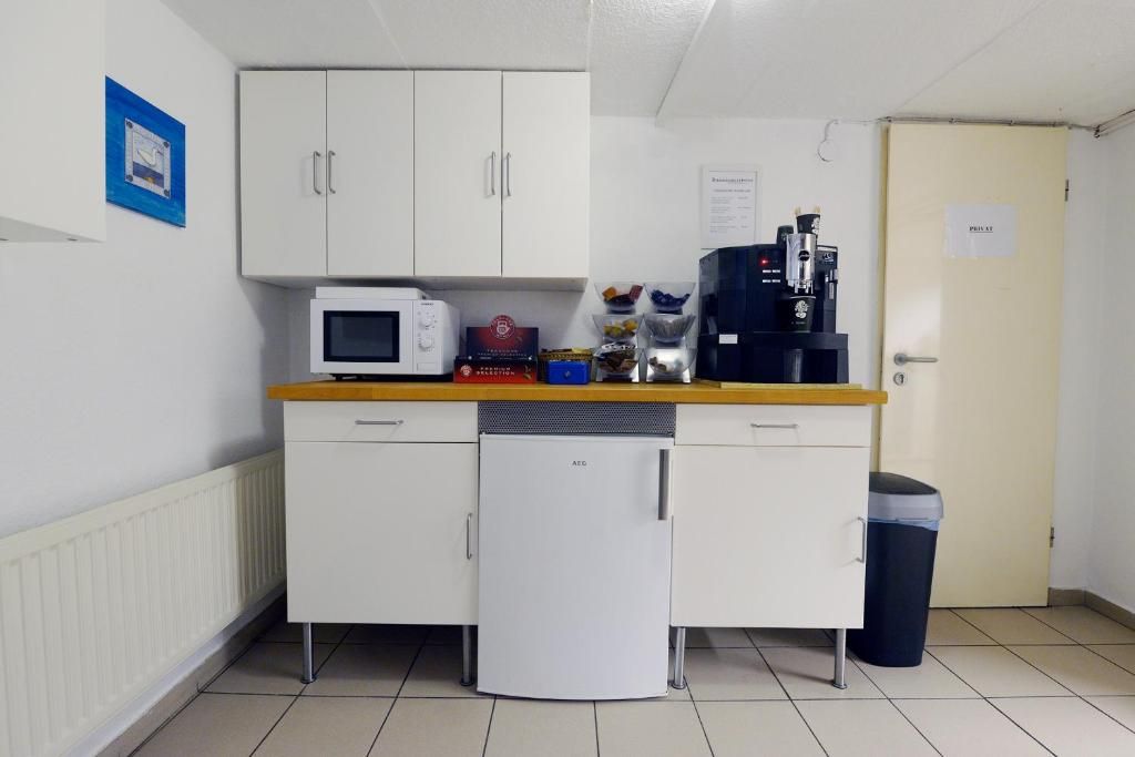 Una kitchenette equipada con microondas, refrigerador y cafetera.