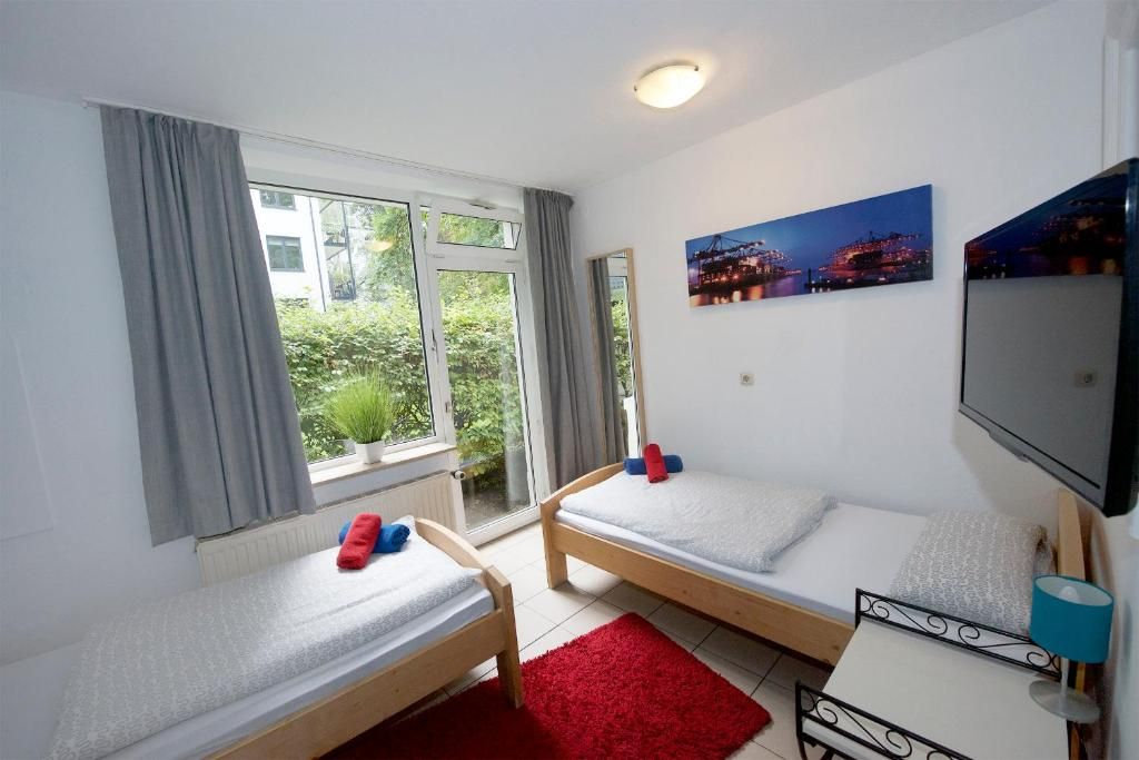 Una habitación con dos camas individuales, televisión y ventana con cortinas.