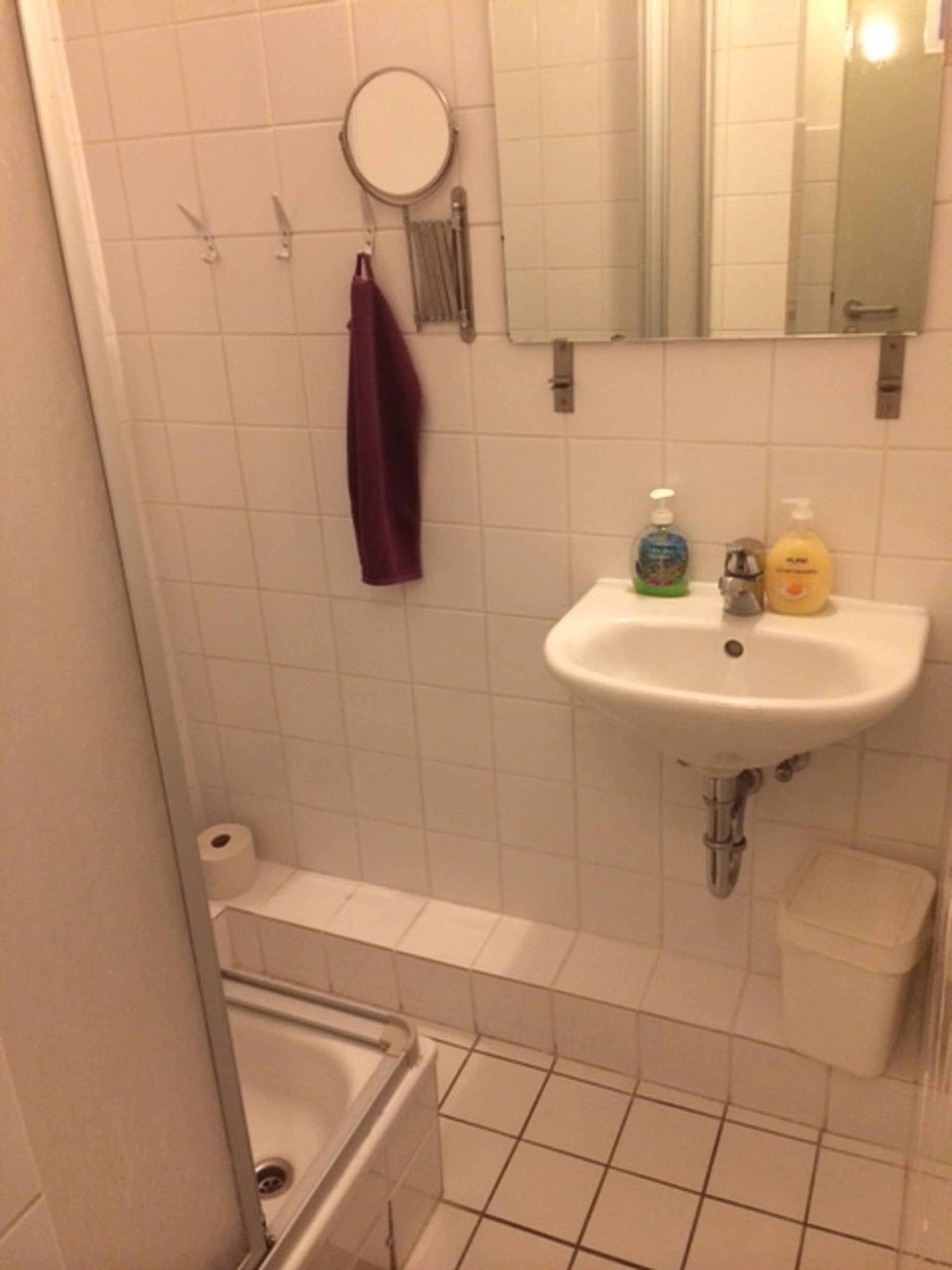 A bathroom with a white sink, a mirror, a round mirror, a purple towel, and a toilet.