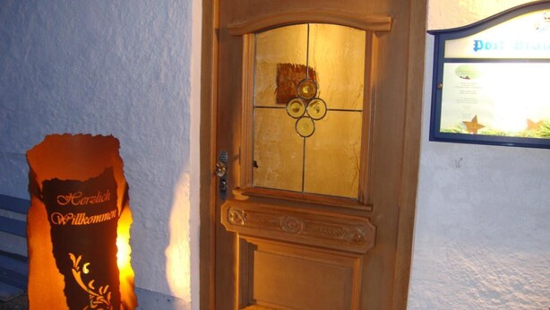 A wooden door with a glass panel and a decorative metal piece above it. - Hotel Schindelberg (Oberstaufen)