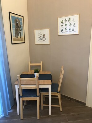 Ein Essbereich mit Tisch und Stühlen, ein gerahmtes Kunstwerk an der Wand und ein Blumentopf auf dem Tisch.