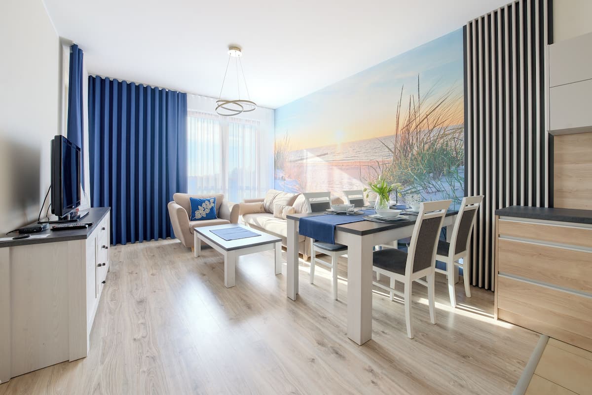 Ein modernes Wohnzimmer mit einer Couch, einem Esstisch und einer Küchenzeile.