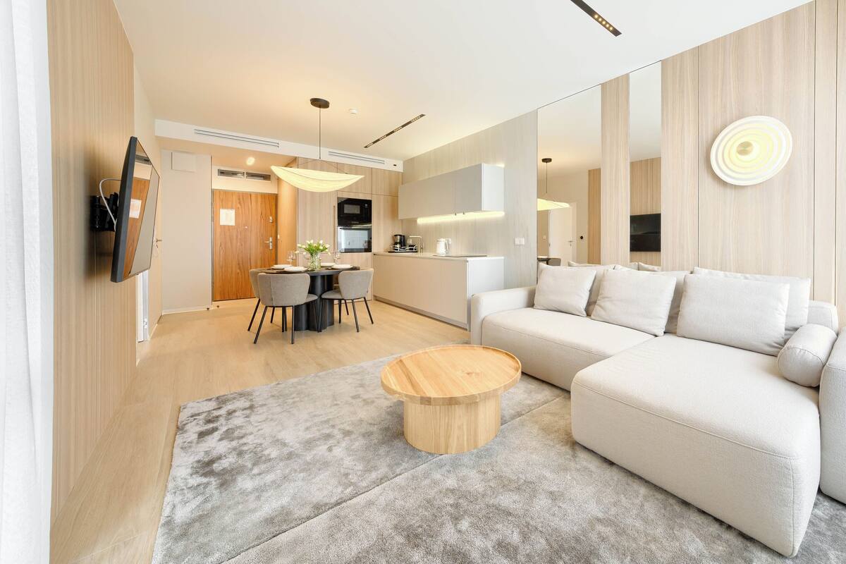 Ein modernes Wohnzimmer mit einer Couch, einem runden Couchtisch und einem Essbereich mit Tisch und Stühlen.