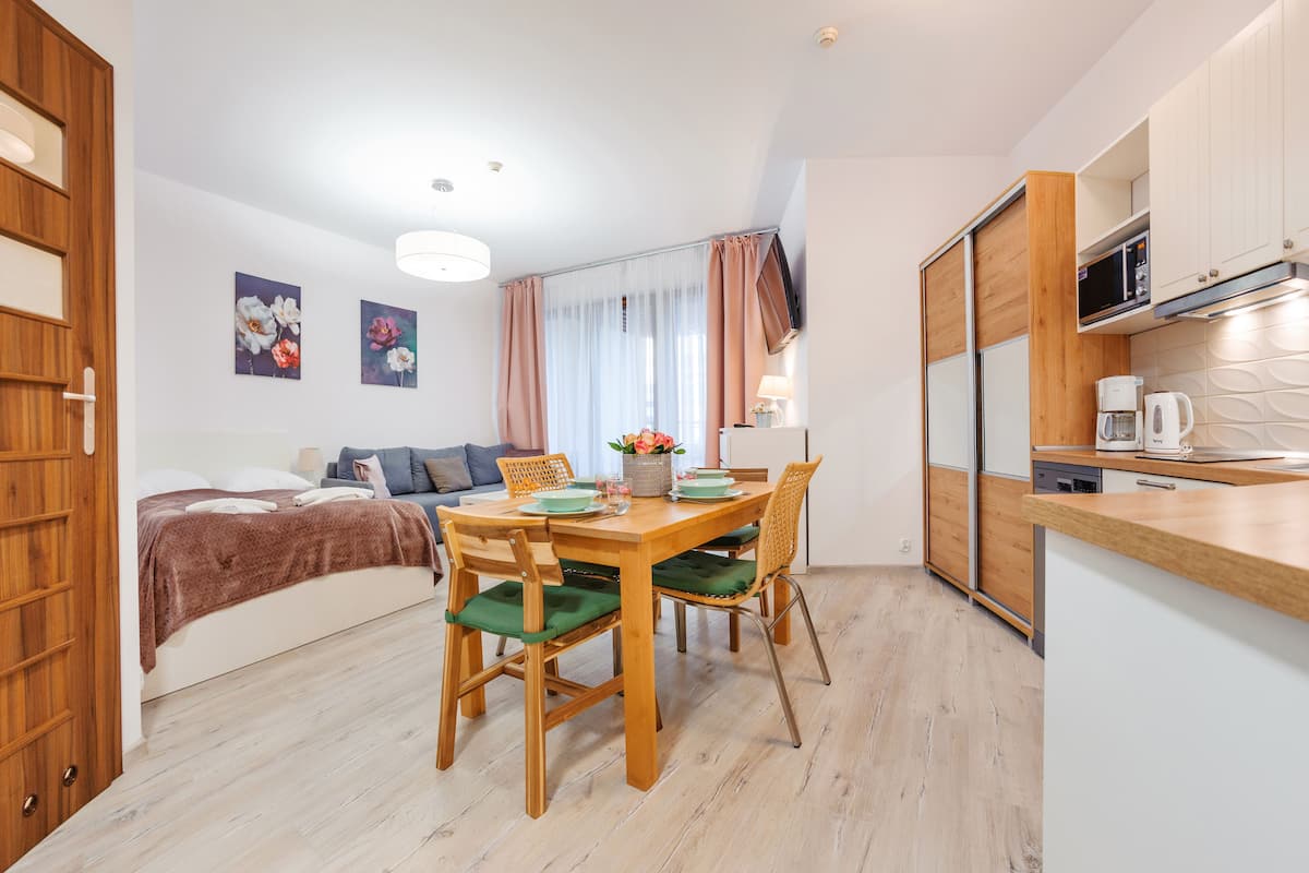 Ein kompakter Wohnraum mit Küchenzeile, Essbereich und Bett.