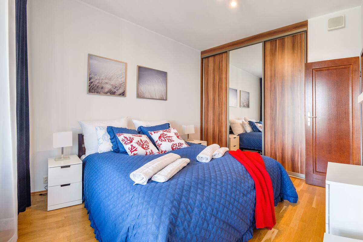 Ein Schlafzimmer mit einem großen Bett, einem Kleiderschrank, einem Nachttisch und einem Sessel.