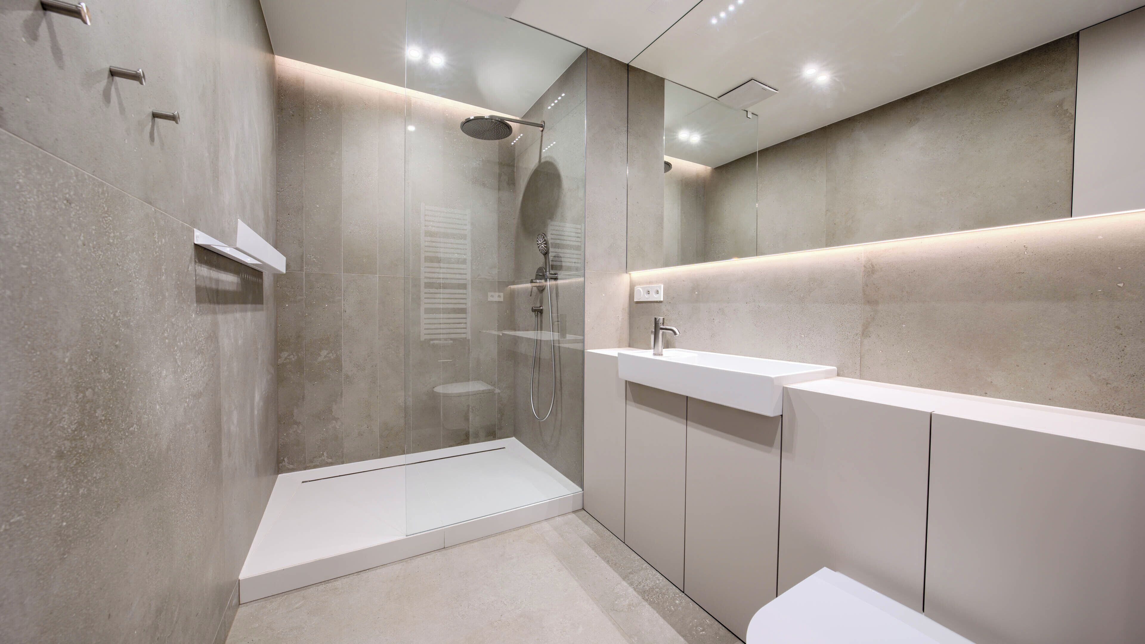 A modern bathroom with a glass-enclosed shower, a white sink, and a vanity.