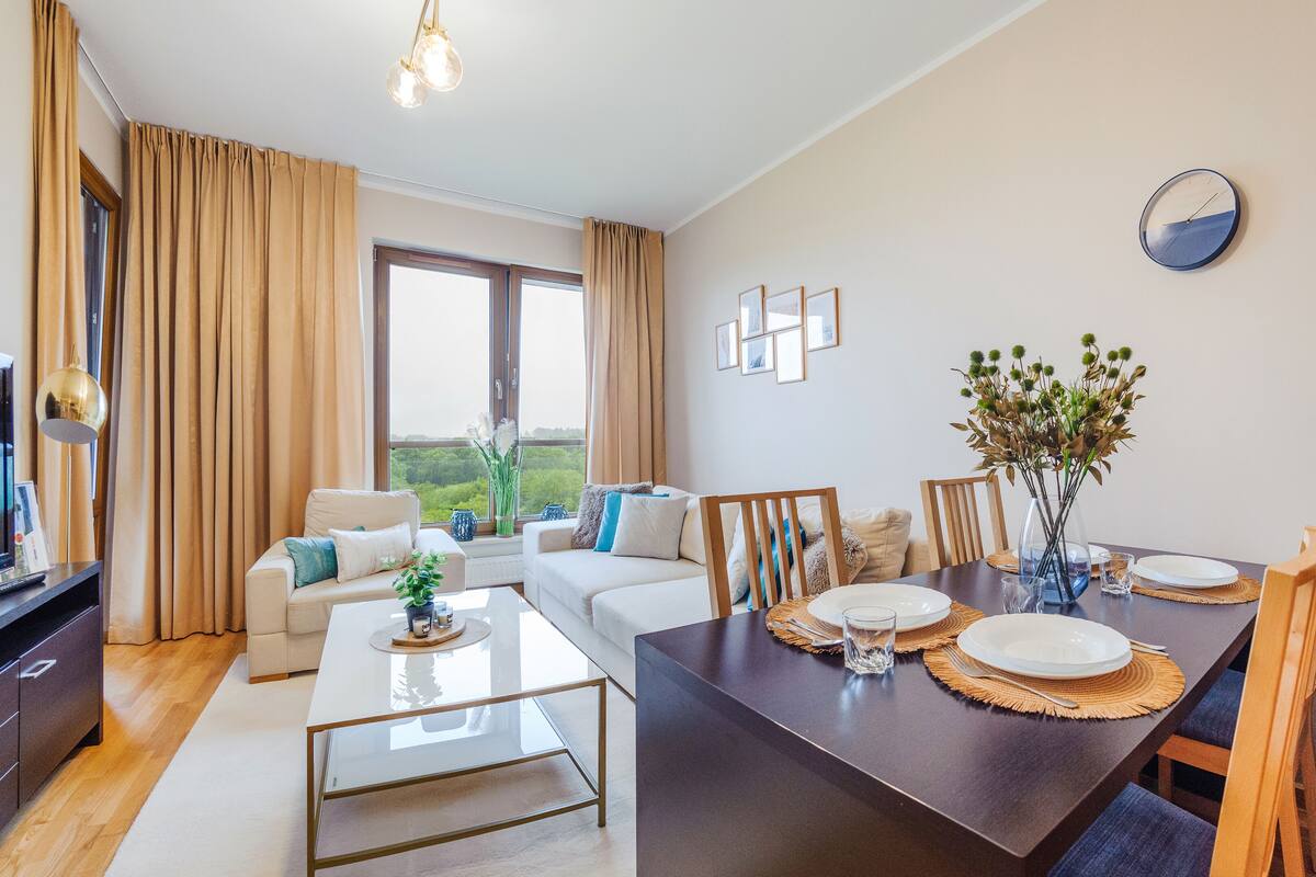 Ein modernes Wohnzimmer mit Essbereich, großen Fenstern und Blick auf Grünflächen.