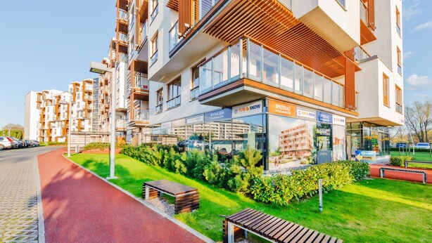 A modern apartment building with balconies, a red bike path, and green landscaping. - Sun & Snow - Olympic Park (Kolobrzeg)