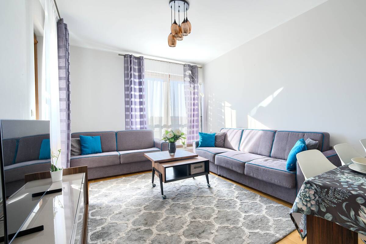 Ein modernes Wohnzimmer mit Sofa, Couchtisch und Esstisch.