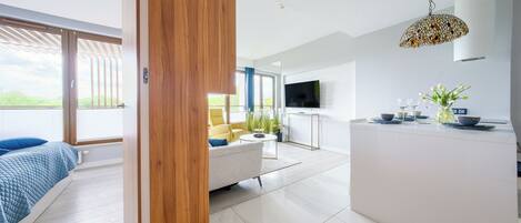 A modern living room with a sofa, a coffee table, and a dining area with a TV and decorative items.
