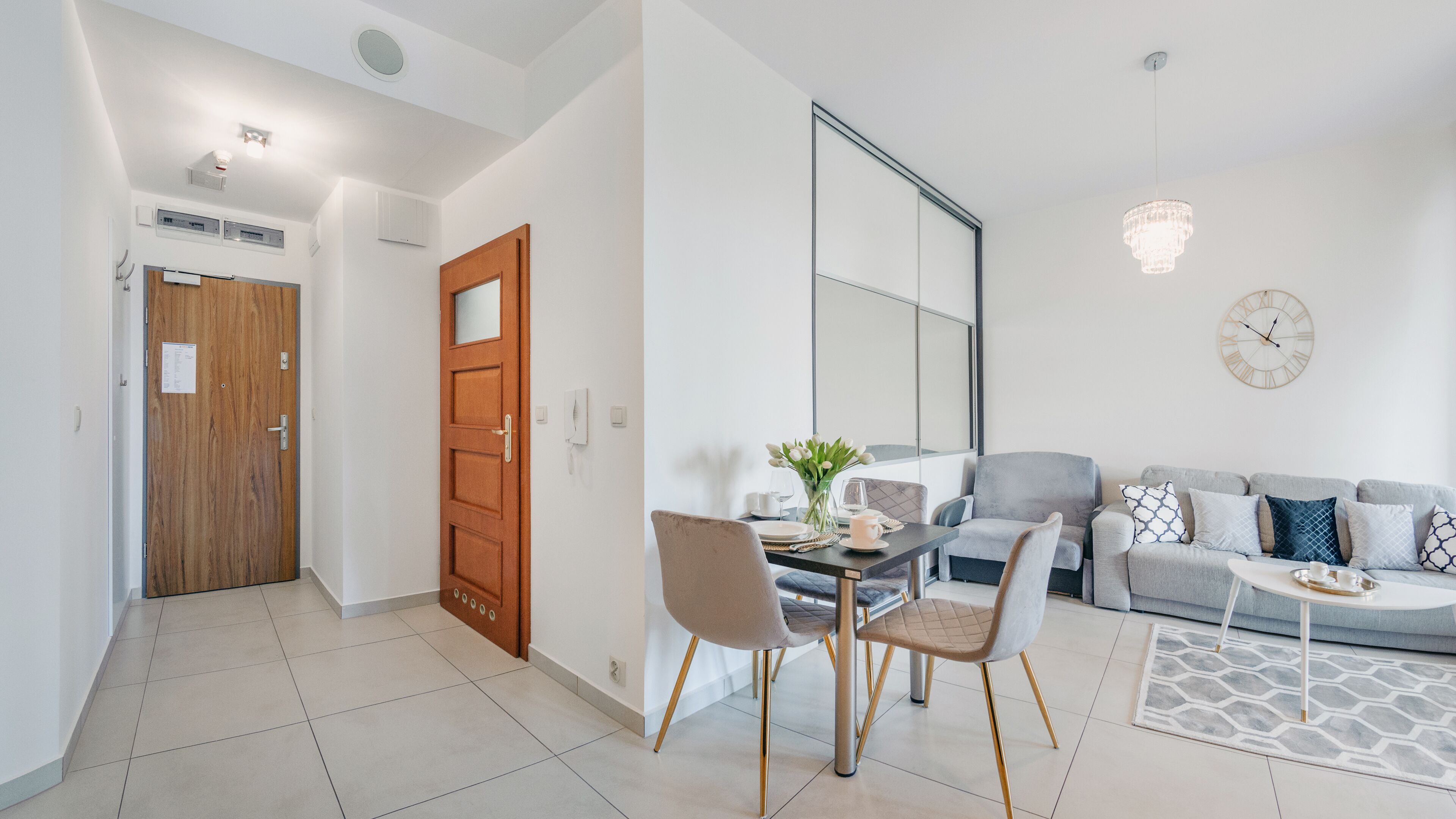 A modern living room with a sofa, chairs, a dining table, and a large mirror.