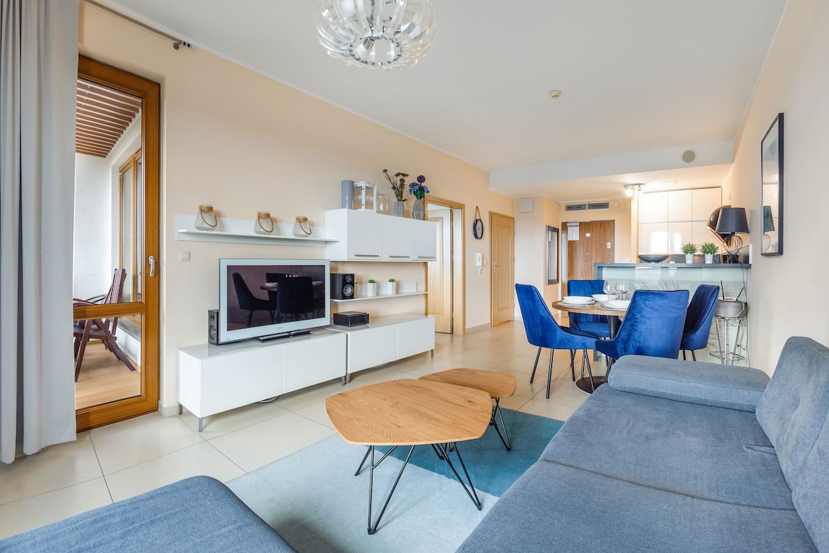 Ein modernes Wohnzimmer mit Fernseher, Sofa und Essbereich.