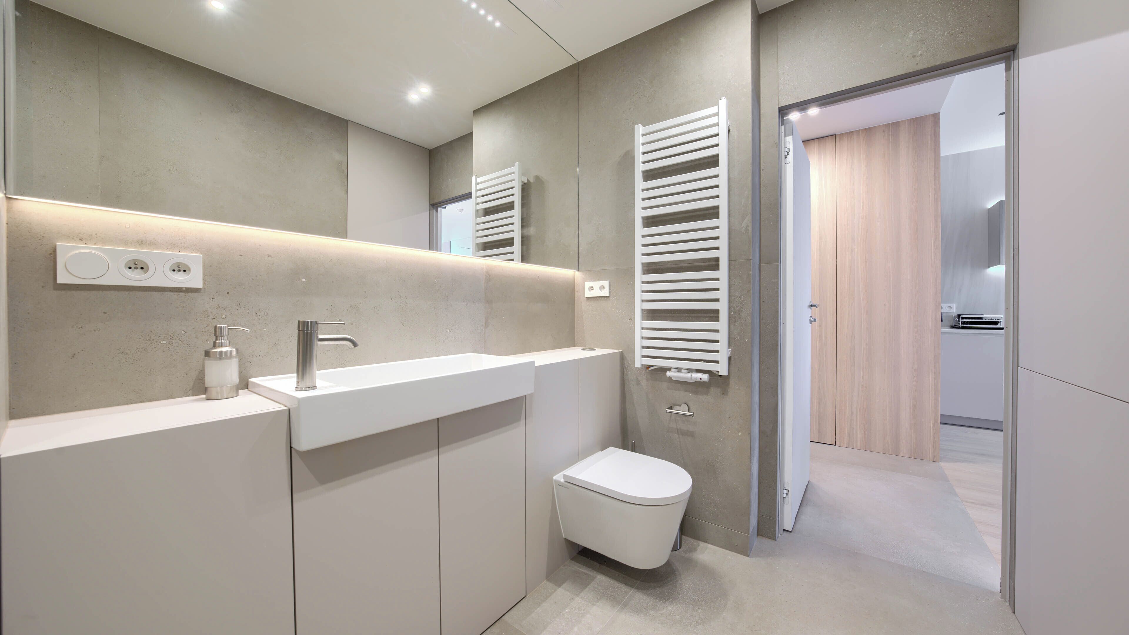 Une salle de bain moderne avec un meuble-lavabo blanc, des toilettes et un espace douche.