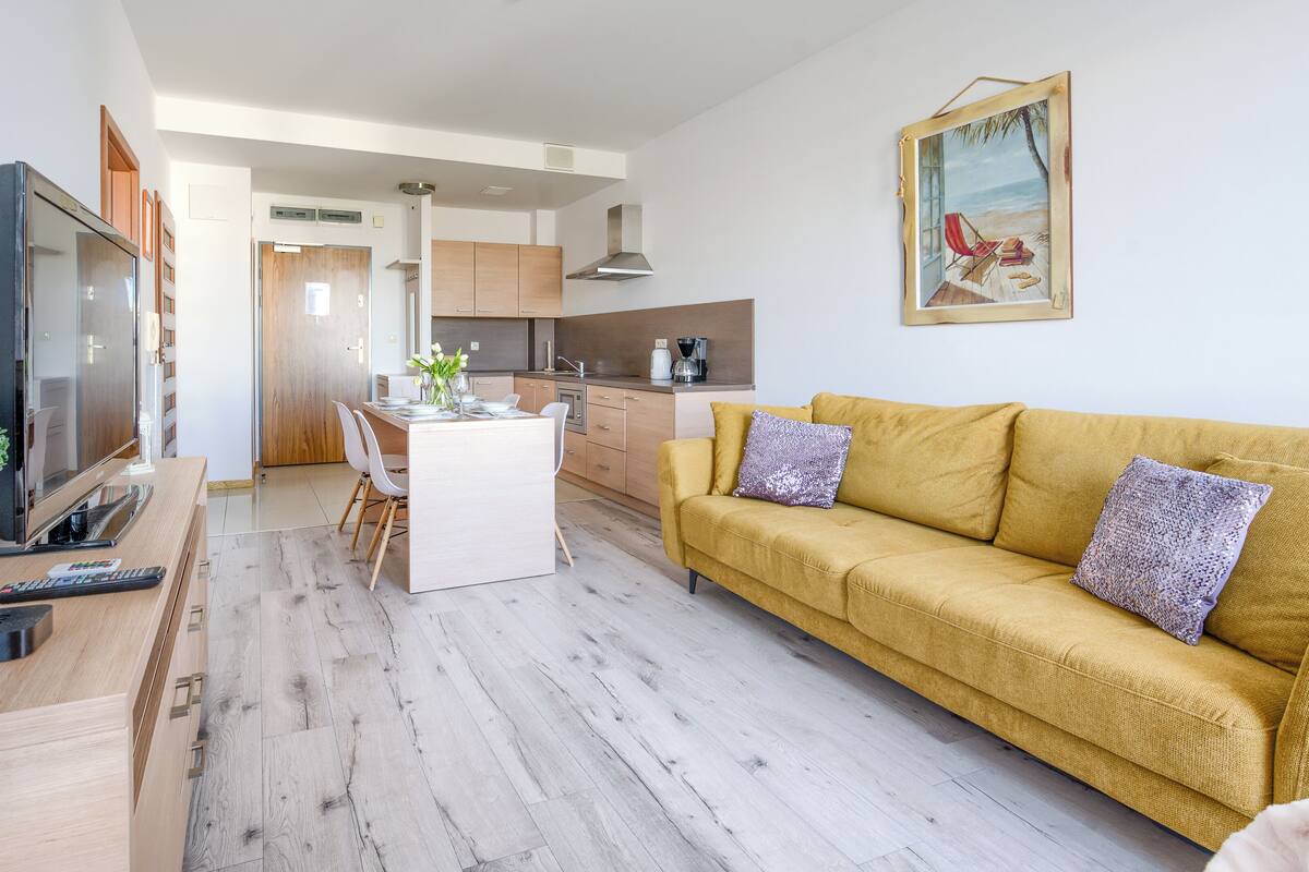 Ein modernes Wohnzimmer mit einer Couch, einem Fernseher und einem Essbereich.