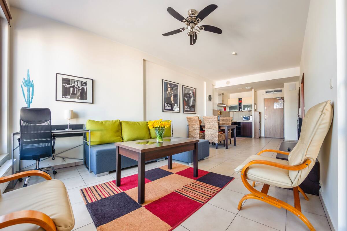 Ein modernes Wohnzimmer mit einer Couch, Sesseln, einem Couchtisch und einem Deckenventilator.